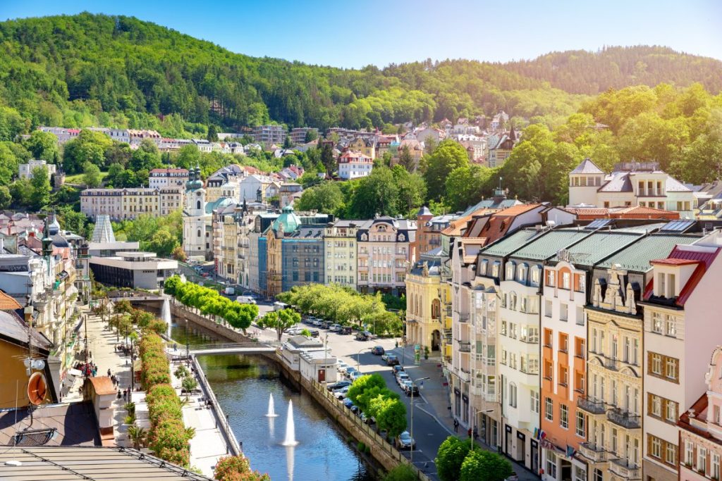 Karlovy Vary med fargerike bygninger langs elvebredden.