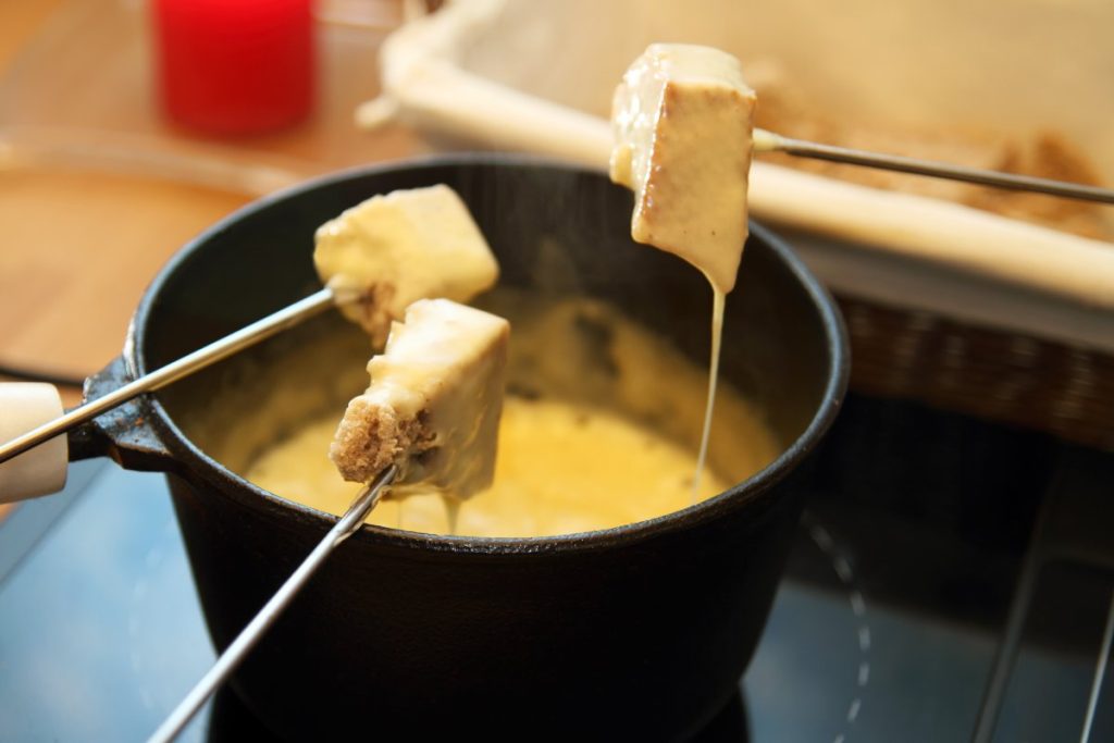 Smeltende ostefondue på gafler servert i tradisjonell gryte.
