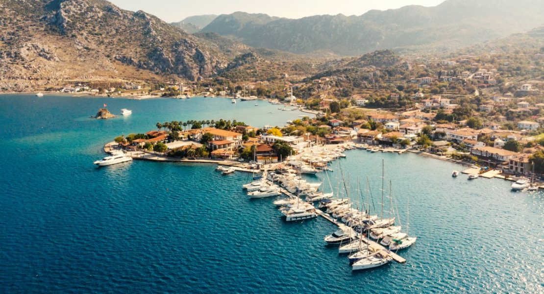 Selimiye fiskerlandsby med båter ankret i turkis bukt.