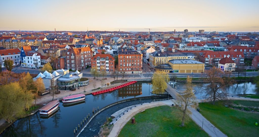 Odense by ved daggry med Odense Å og Munke Mose park.