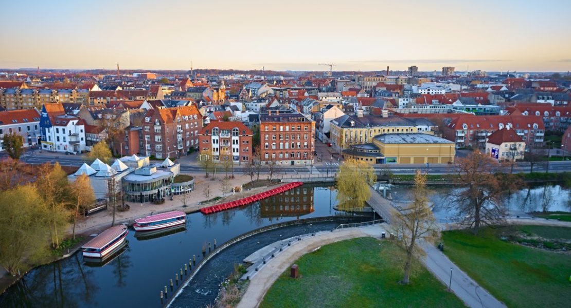 Odense by ved daggry med Odense Å og Munke Mose park.