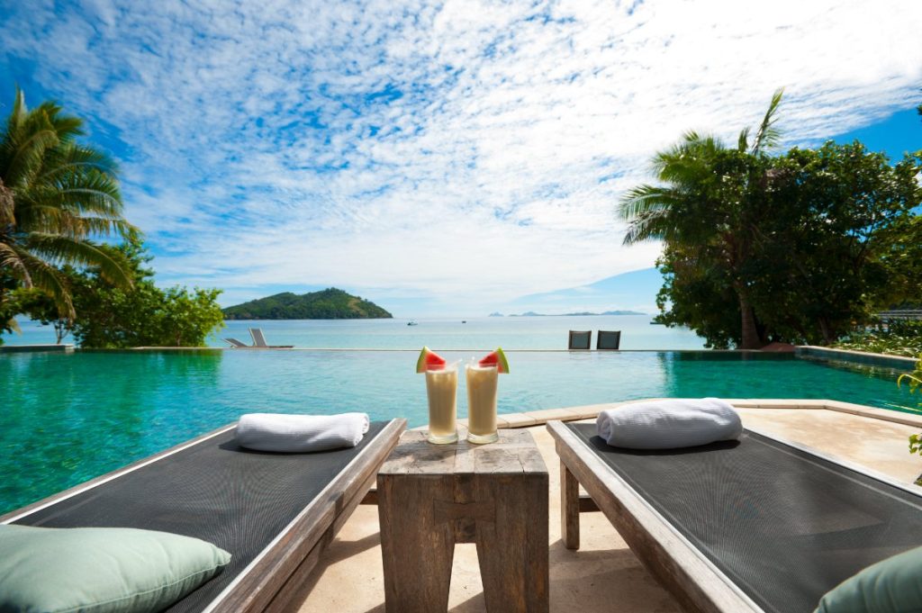Solsenger og fargerike cocktails ved bassengkanten på thailandsk resort.