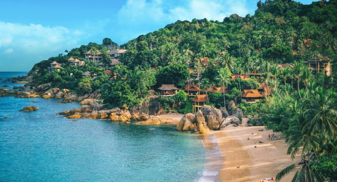Palmelinjet strand strekker seg langs turkisblått hav på Koh Samui.