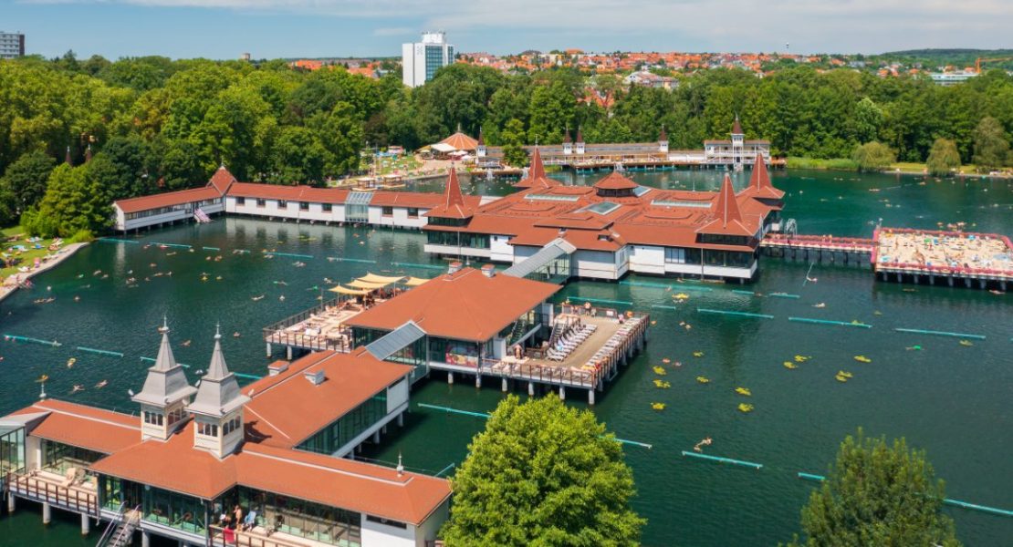 Hévíz termalbad med dampende vann omgitt av grønn vegetasjon.