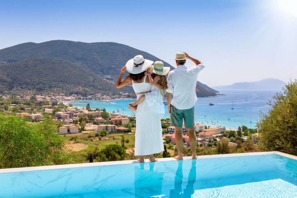 Familie nyter sommerdagen ved bassenget på ferie i Hellas.