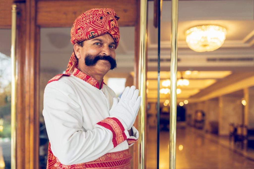 Indisk portier ønsker gjester velkommen ved hotellinngangen i Agra, India.
